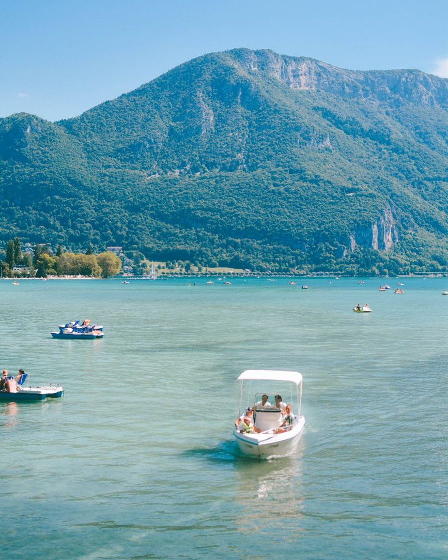 Bateau de croisière touristique naviguant sur le lac d'Annecy avec les montagnes du massif des Bauges en arrière-plan