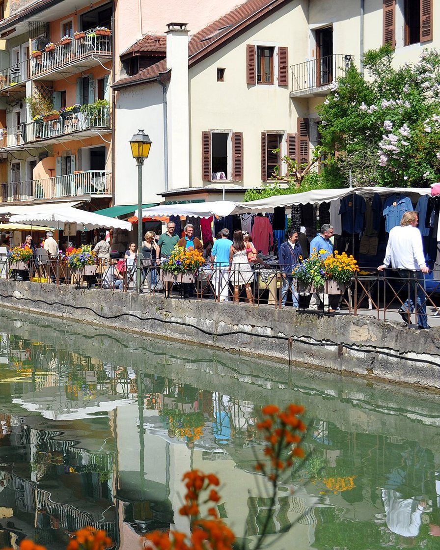 Canaux du Thiou bordés de façades colorées dans la vieille ville d'Annecy, passerelles en pierre et terrasses de café au bord de l'eau