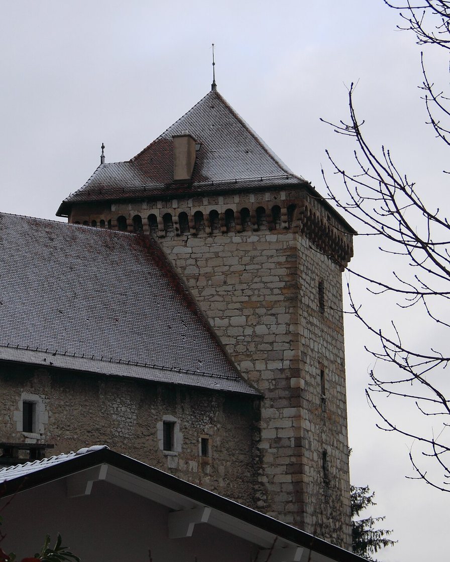 Musée-Château d'Annecy et ses tours en pierre sous un ciel gris, avec les toits de la vieille ville en contrebas