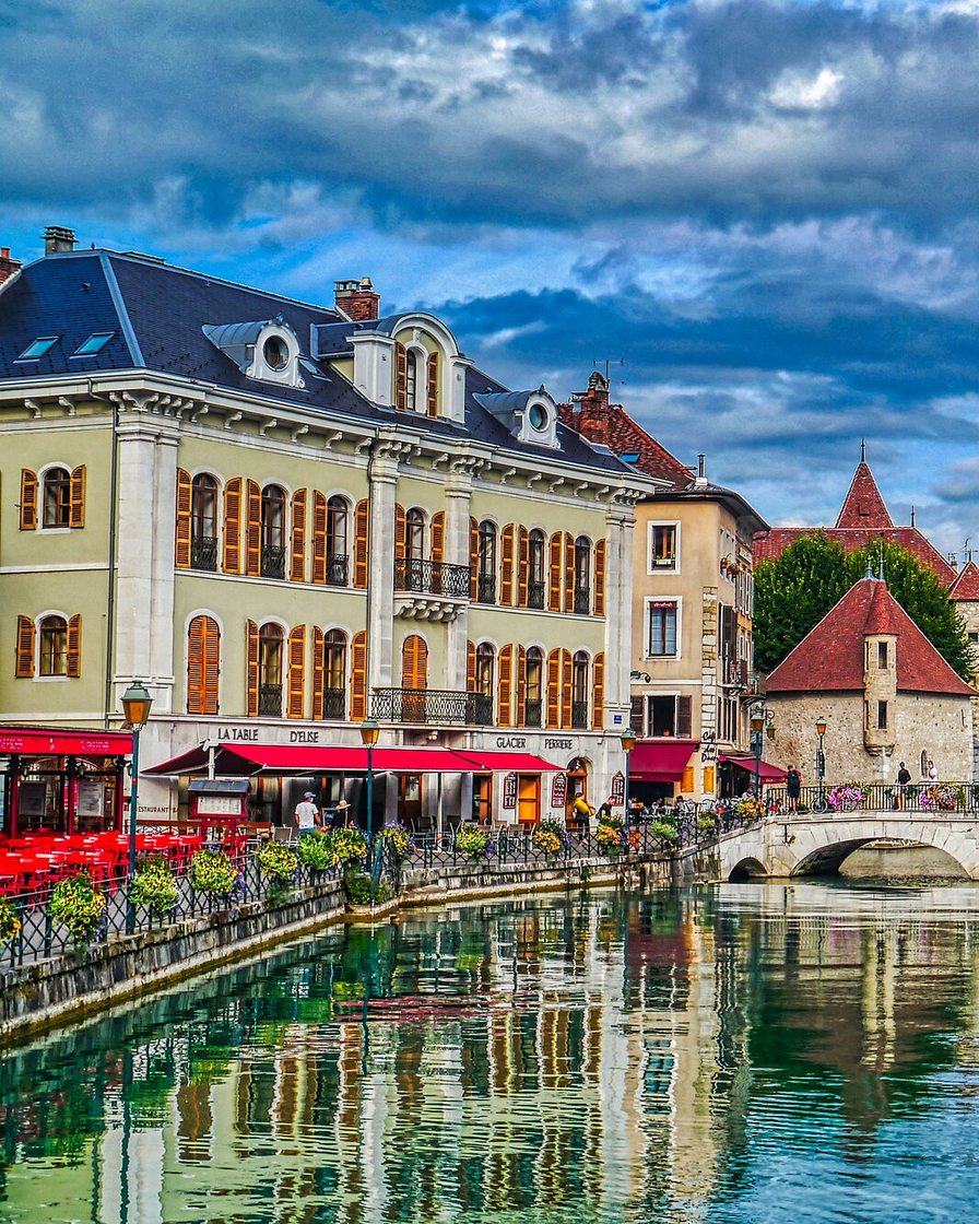 Palais de l'Île sur le canal du Thiou à Annecy, reflets des façades dans l'eau verte par une matinée claire